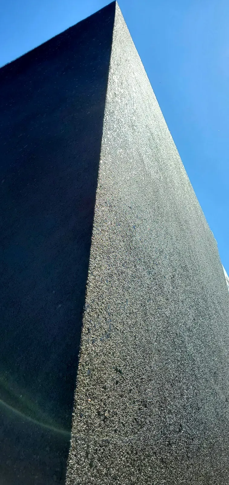 Close-up of a dark textured stucco column against the sky
