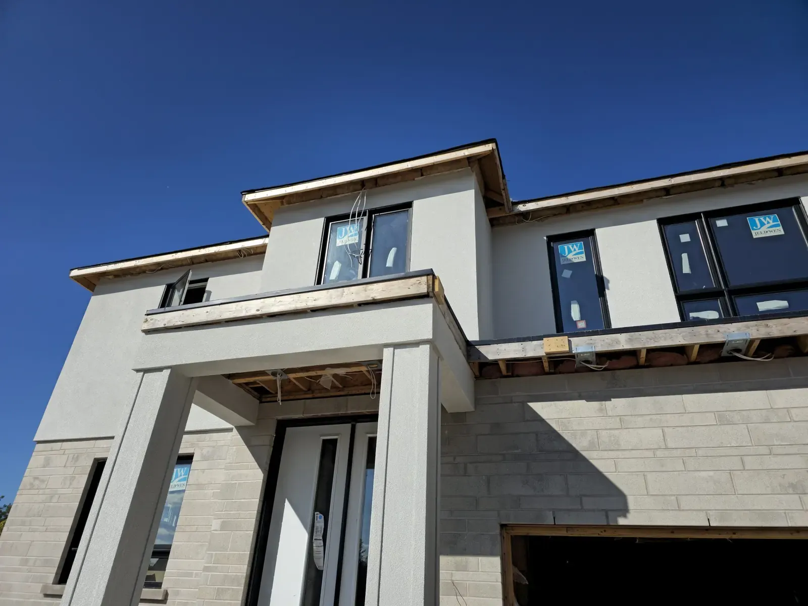 Modern two-storey stucco home with stone base and tall entry columns