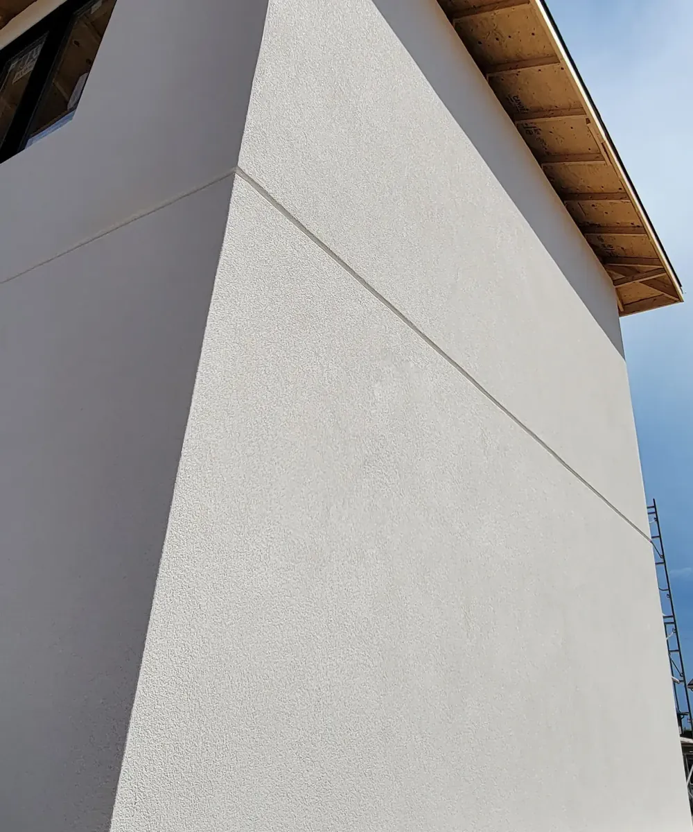 Crisp smooth stucco corner with a reveal line under a wood soffit